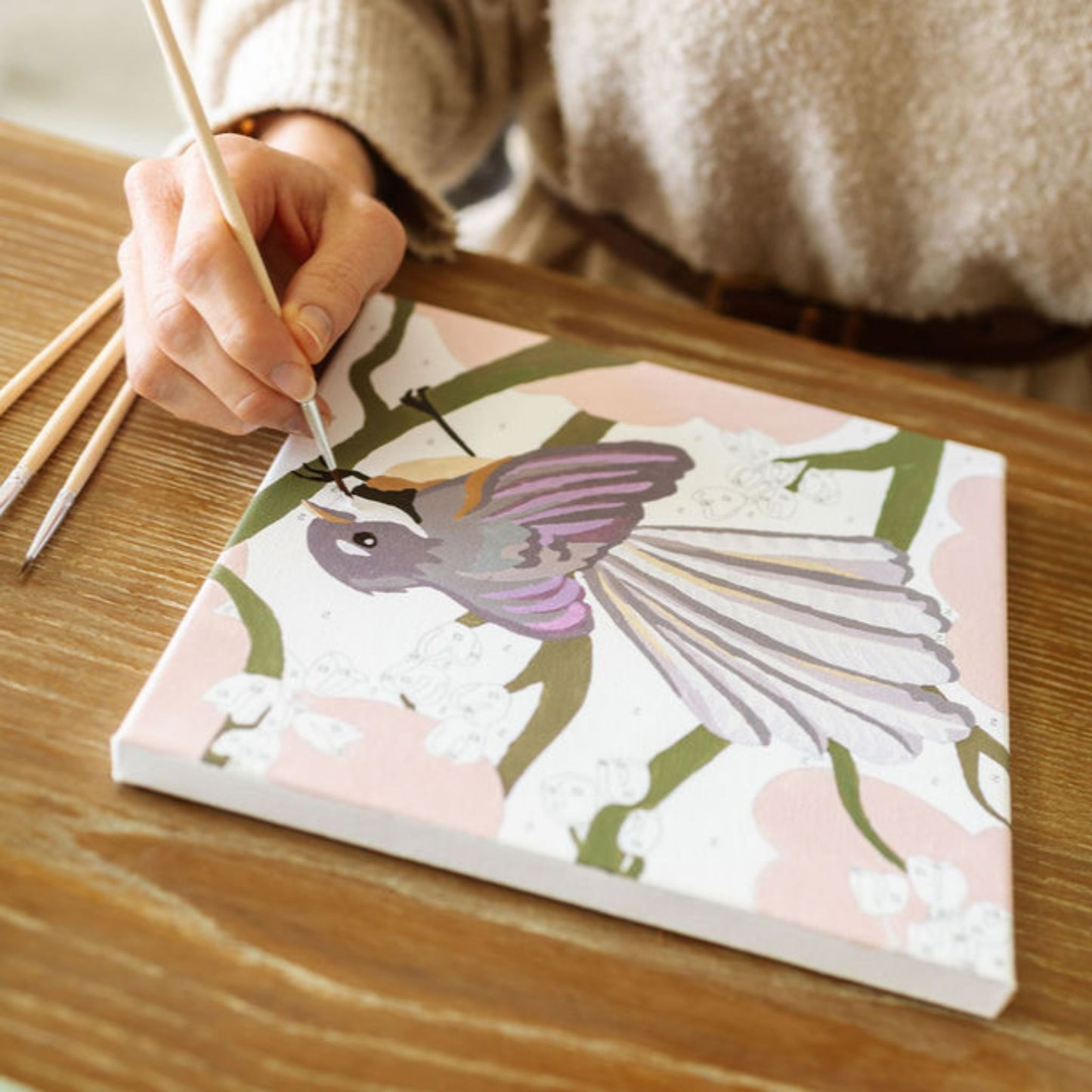 Person coloring a notebook with a purple bird design on a wooden table.
Adventure Collections Fantail Paint By Numbers Kit – 20 x 20cm
