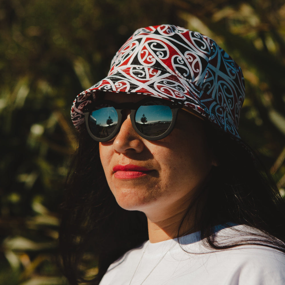 Person wearing a patterned Bucket Hat Mangapore and sunglasses with a blurred natural background