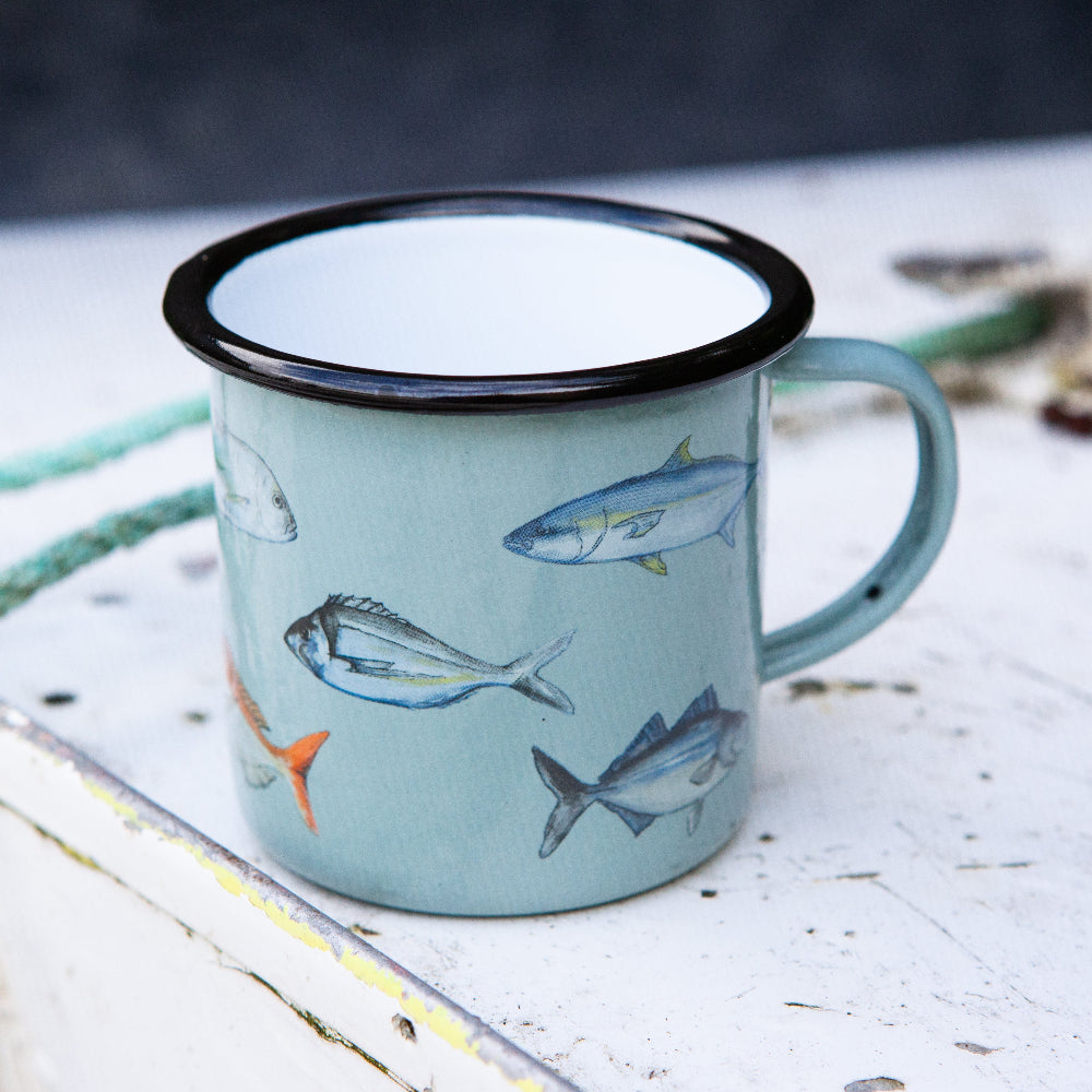 Blue enamel mug fishing club with fish illustrations on a wooden surface with ropes and natural elements.
