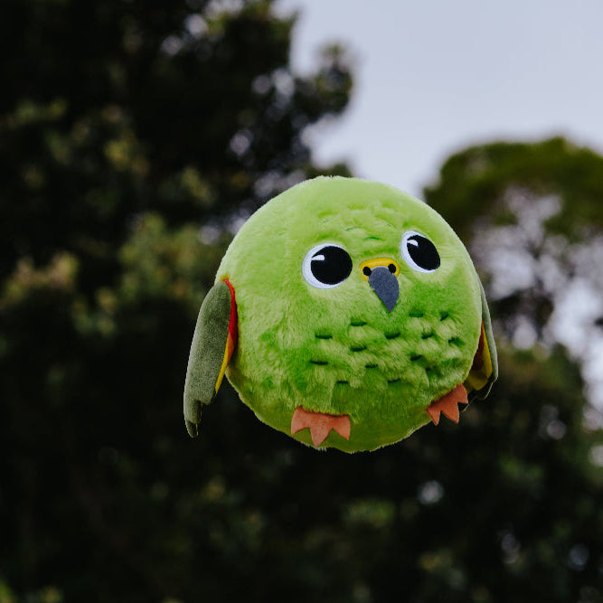 Green plush parrot toy against a blurred natural background