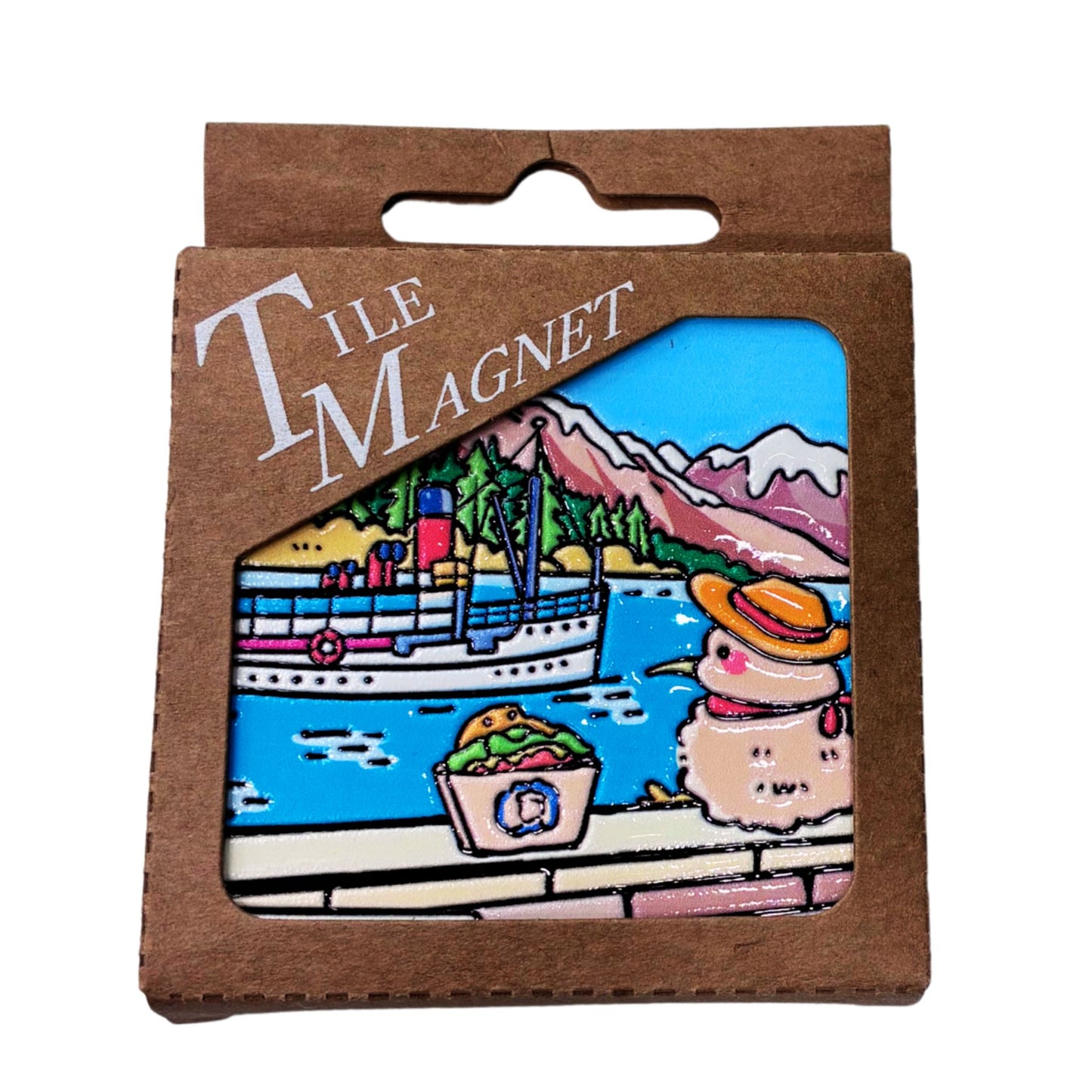 A square ceramic tile magnet in its original brown cardboard packaging, featuring a kiwi illustration of a snowy landscape with mountains, a boat, and a snowman.