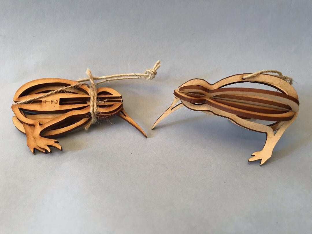 Two wooden kiwi bird ornaments on a light gray background