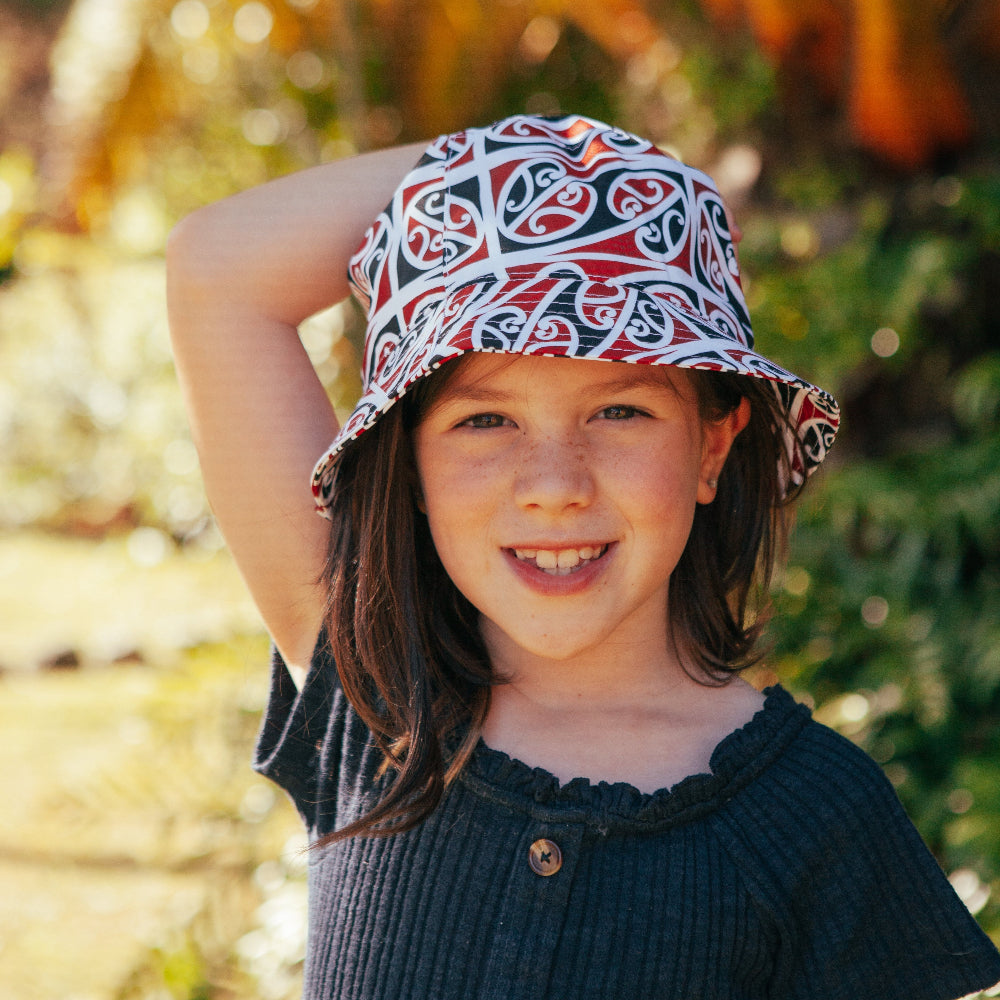 Young girl wearing a patterned hat outdoors with blurred natural background