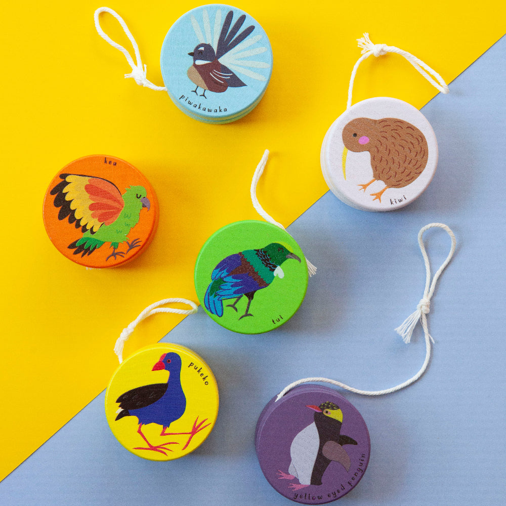 Set of colorful wooden yoyos with bird illustrations on a yellow and blue background