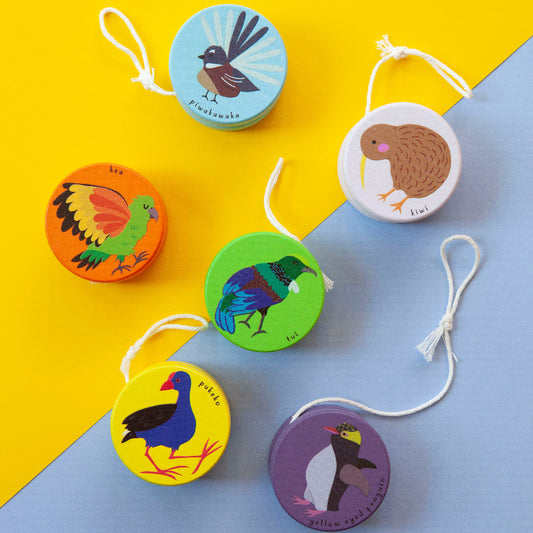 Set of colorful wooden yoyos with bird illustrations on a yellow and blue background