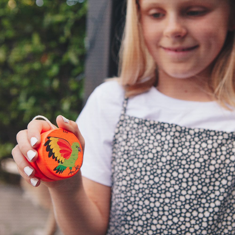 Young girl holding an orange yoyo toy with a dragon design outdoors