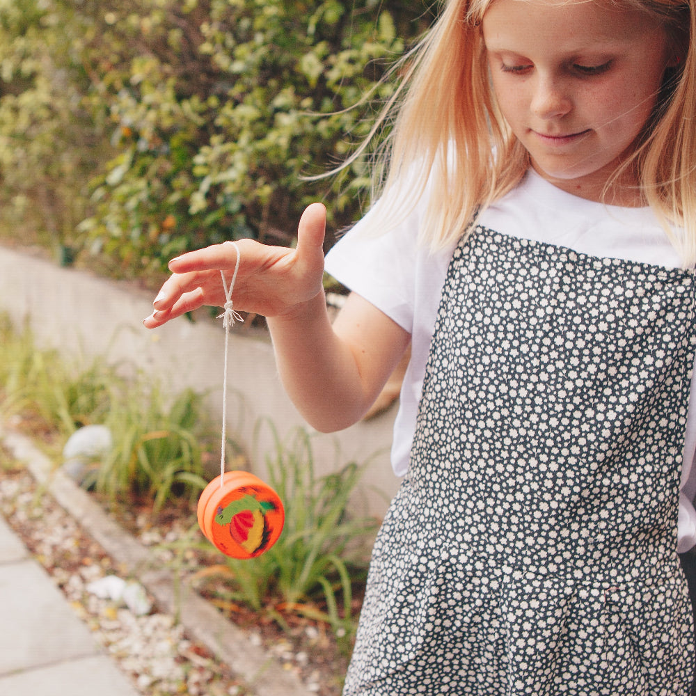 Young girl playing with a colorful yoyo toy outdoors
