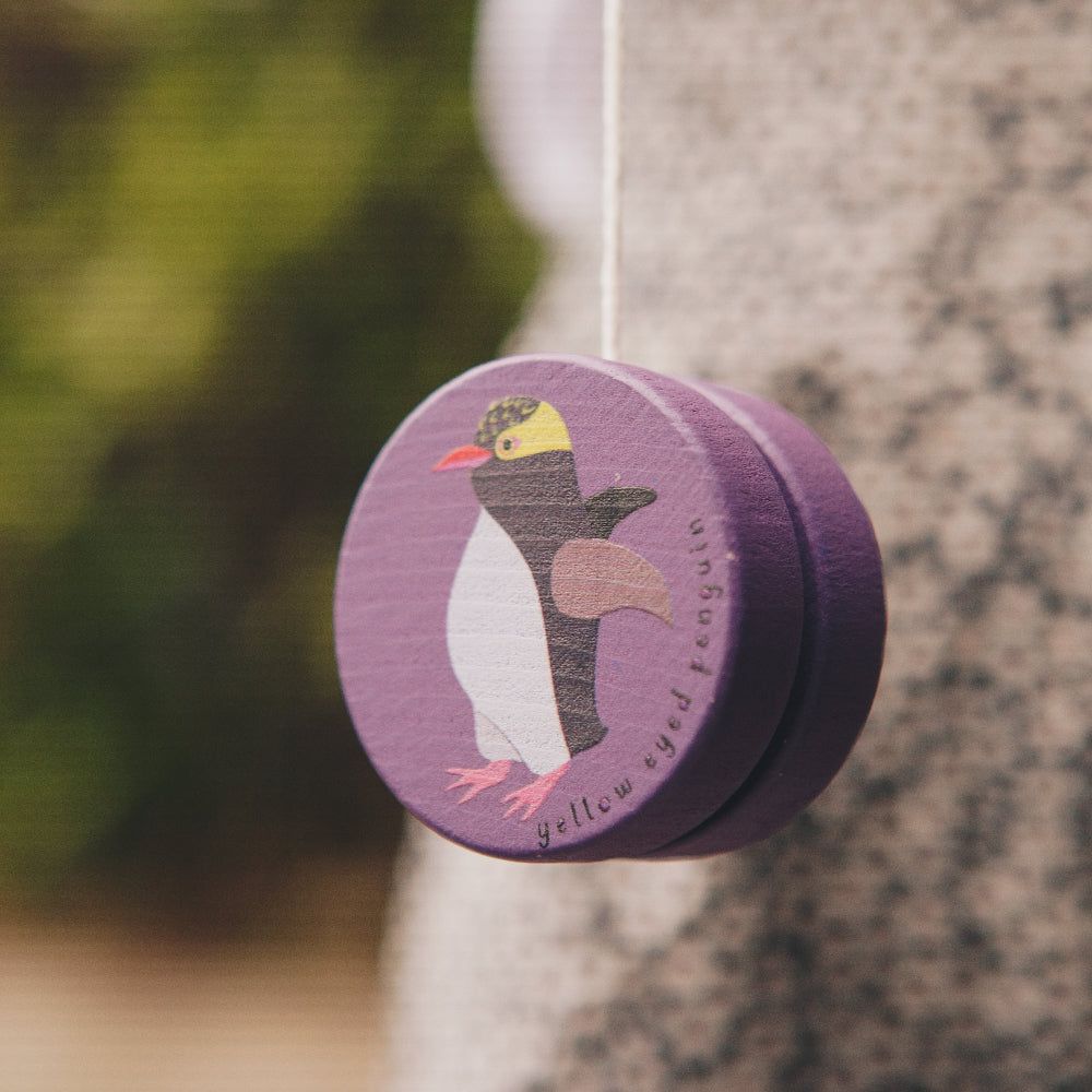 Purple yoyo with a penguin design hanging on a tree
