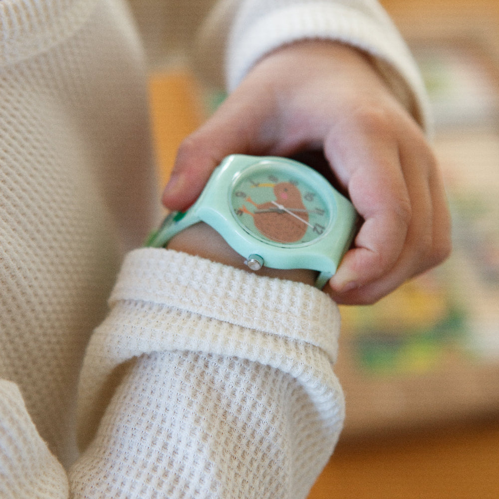 Person wearing a light green kiwi watch with a blurred background