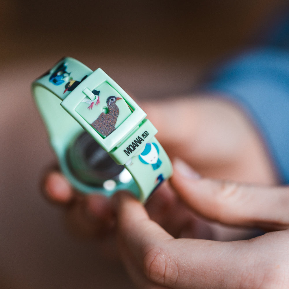 Close-up of a hand holding a small green device with cartoon characters on a blurred background