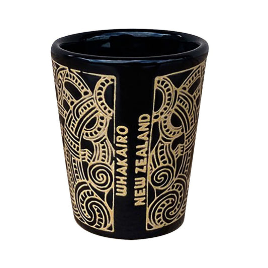 Black shot glass with gold patterns and 'Wakairo New Zealand' text on a white background