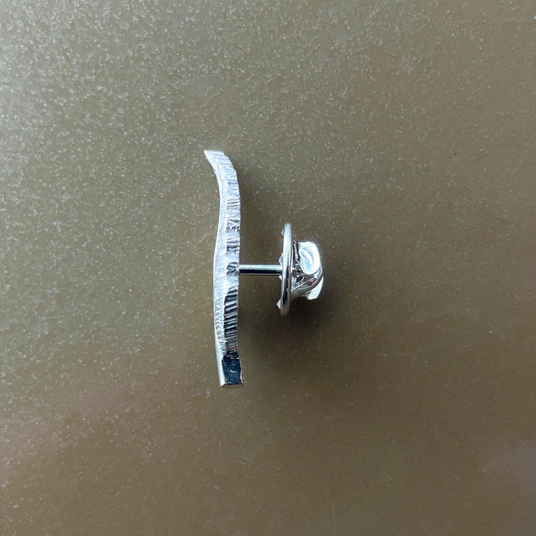 Silver earring on a reflective surface