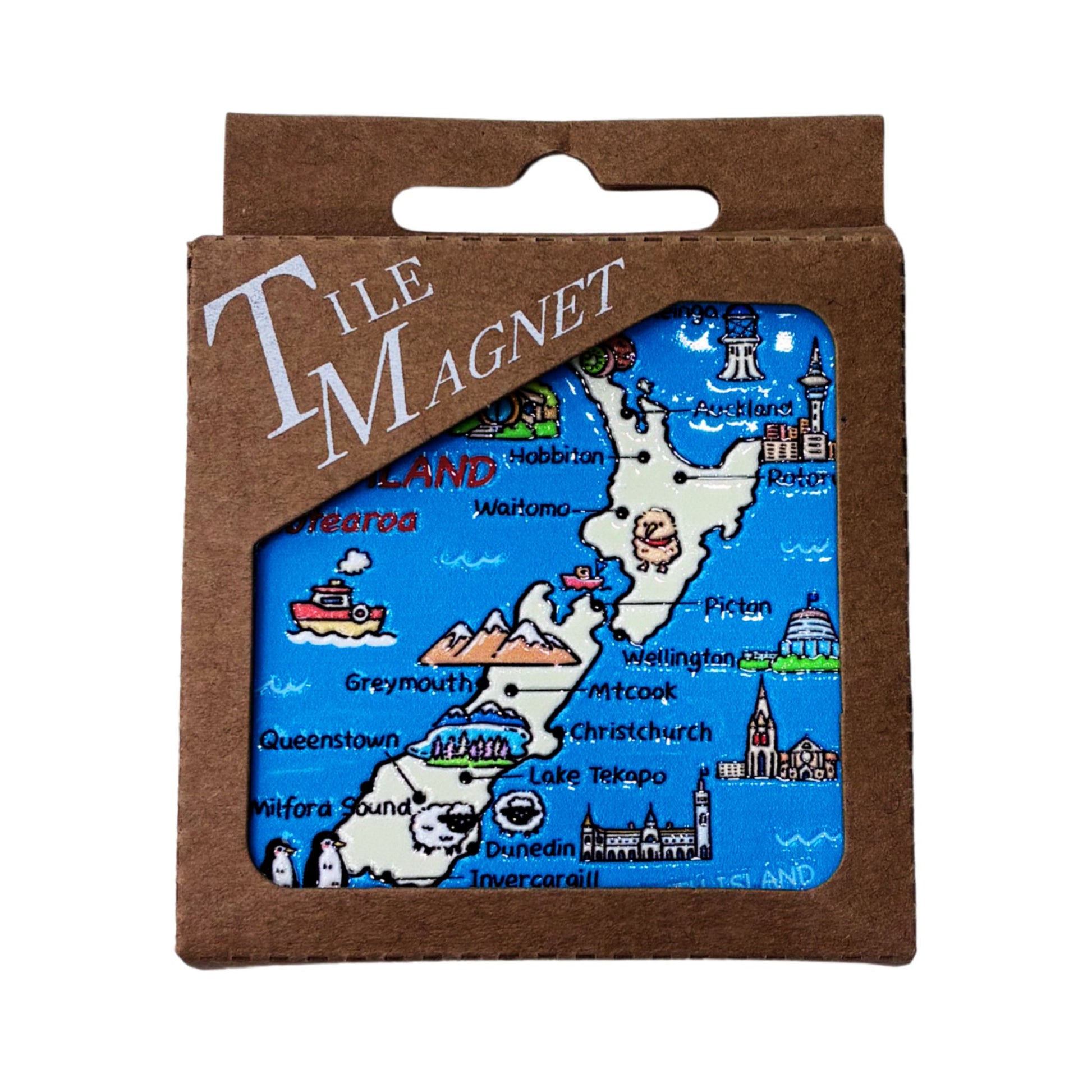 A square tile magnet in its brown cardboard packaging, featuring a colorful illustrated map of New Zealand with labeled cities, landmarks, and lakes.