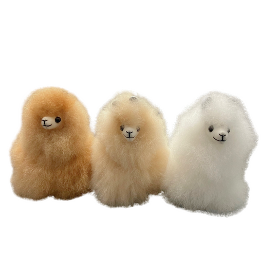 Three alpaca key rings in beige, white, and brown colors, made from alpaca hair, displayed side by side.