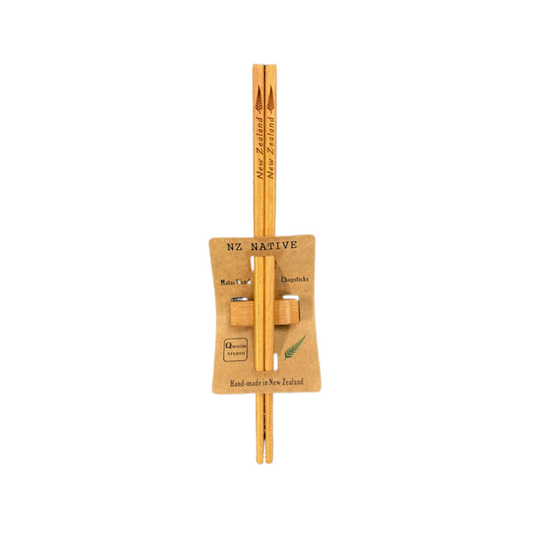 A pair of chopsticks with a silver fern leaf pattern, attached to a cardboard holder with 'Native' and 'New Zealand' printed on it.