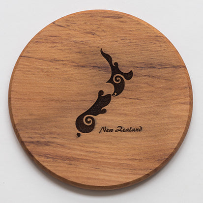 A round wooden coaster with a carved pattern resembling a stylized bird and the text 'NEW ZEALAND' in the center, on a clear background.