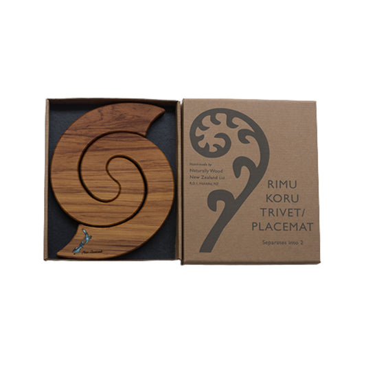 Wooden trivet with koru design on a cardboard box packaging.