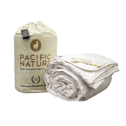 A beige and white Pacific Nature alpaca duvet cover and a smaller branded bag, both displaying the brand's logo and information.